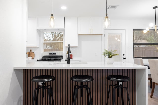 kitchen with visible vents, a sink, gas range, and white cabinetry