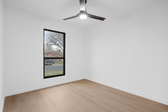 spare room featuring wood finished floors, a ceiling fan, and baseboards