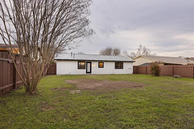 back of property featuring a fenced backyard and a lawn