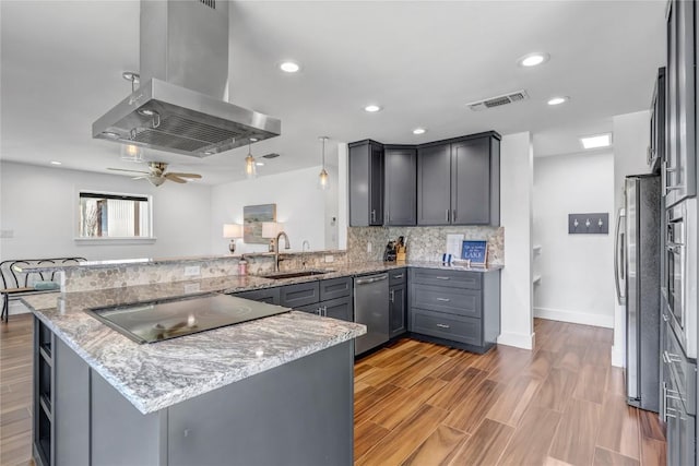 kitchen with visible vents, appliances with stainless steel finishes, a sink, island range hood, and a peninsula