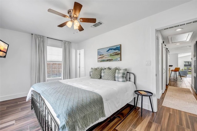 bedroom with ceiling fan, wood finished floors, visible vents, and baseboards