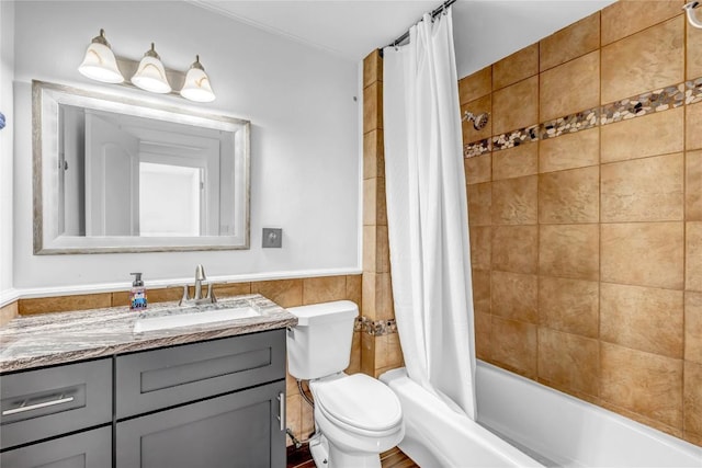 full bathroom with toilet, a wainscoted wall, vanity, tile walls, and shower / bathtub combination with curtain