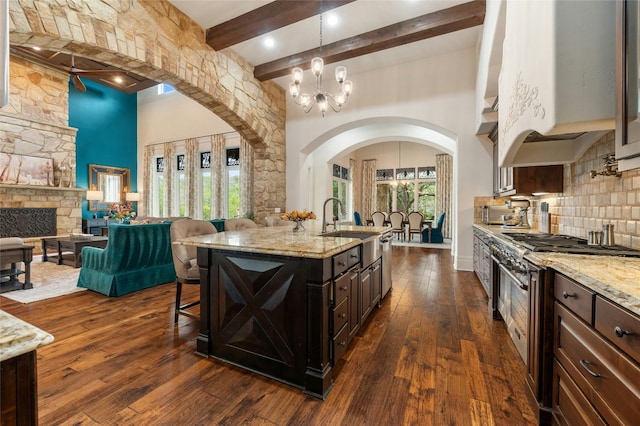 19520 Tessa Hts, Spicewood, TX 78669 - kitchen featuring arched walkways, high end range, a sink, a breakfast bar, and beam ceiling