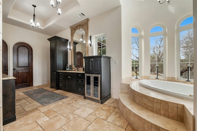 19520 Tessa Hts, Spicewood, TX 78669 - bathroom with wine cooler, vanity, a bath, stone tile floors, and a raised ceiling