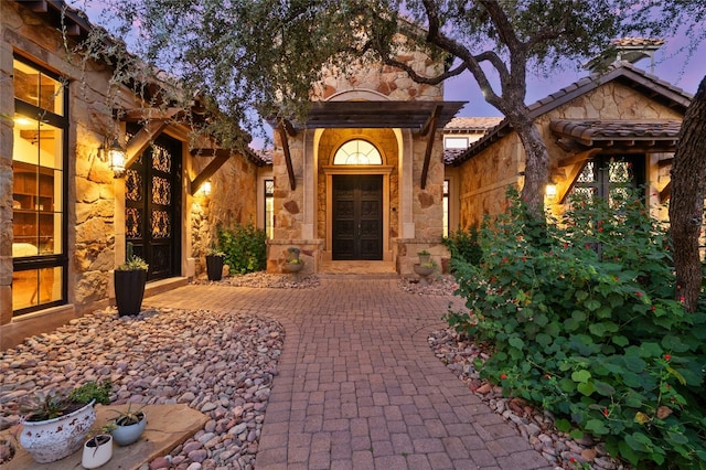 view of exterior entry with stone siding and a tile roof