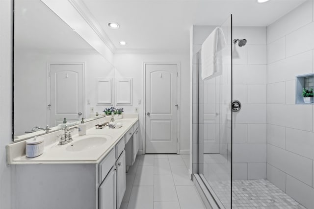 bathroom featuring crown molding, double vanity, a sink, tile patterned flooring, and tiled shower