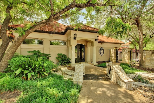 mediterranean / spanish house featuring a gate, french doors, a tile roof, and stucco siding