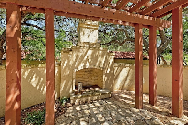 view of patio featuring exterior fireplace, fence, and a pergola