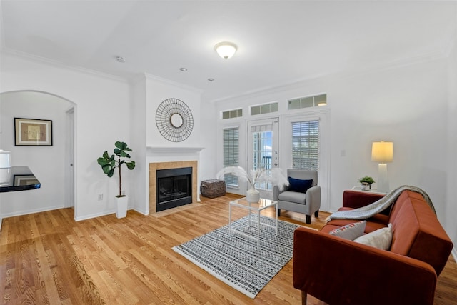 living room with wood finished floors, visible vents, baseboards, ornamental molding, and a tiled fireplace