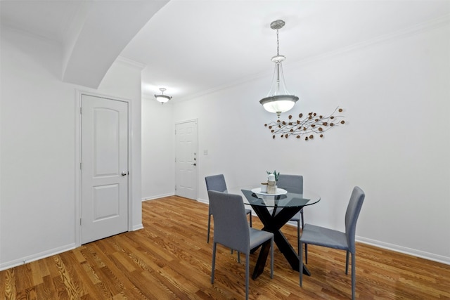 dining space featuring crown molding, baseboards, and wood finished floors