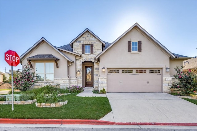 view of front of property with stone siding, a front lawn, concrete driveway, and stucco siding