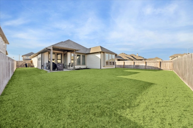 back of house featuring a patio area, a fenced backyard, a shingled roof, and a lawn