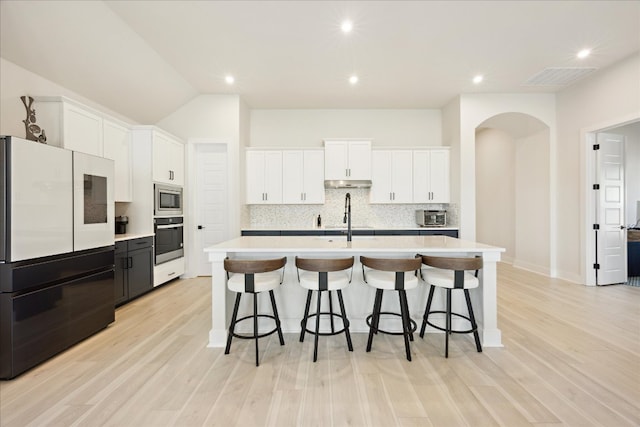 kitchen with oven, white cabinets, light countertops, freestanding refrigerator, and stainless steel microwave