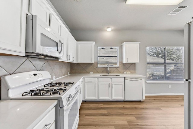 kitchen featuring light countertops, white appliances, a sink, and visible vents