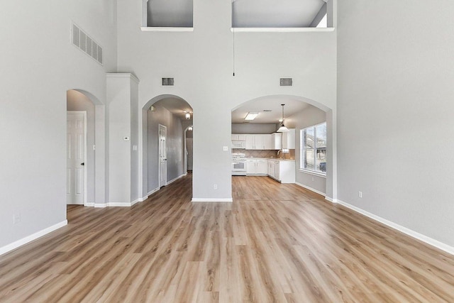 unfurnished living room featuring light wood-style floors, visible vents, and baseboards