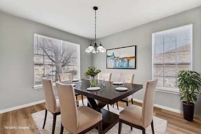 dining room with baseboards, light wood-type flooring, and an inviting chandelier