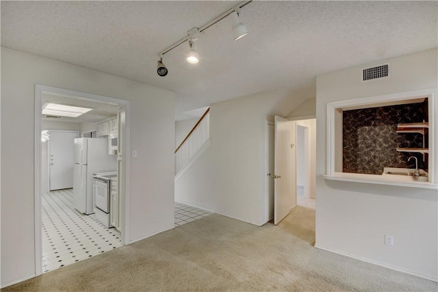 empty room with visible vents, stairway, light carpet, a sink, and a textured ceiling