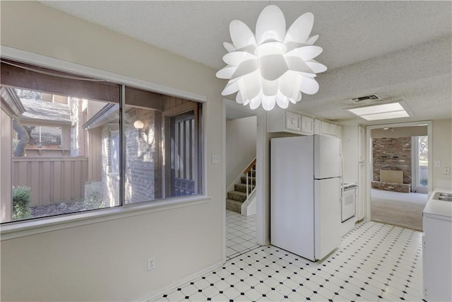 kitchen with visible vents, light floors, a textured ceiling, and freestanding refrigerator