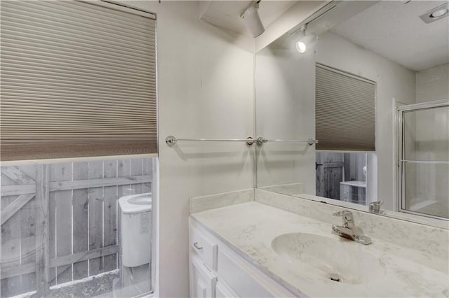 bathroom with toilet, a stall shower, and vanity