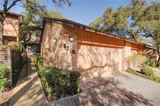 view of property exterior with a garage, driveway, and brick siding