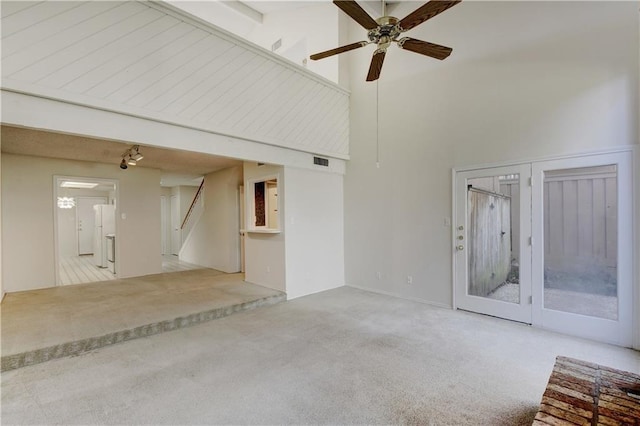 unfurnished room with carpet, visible vents, stairway, a high ceiling, and ceiling fan