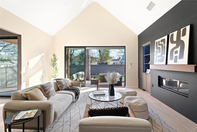 living room with a large fireplace, high vaulted ceiling, plenty of natural light, and visible vents