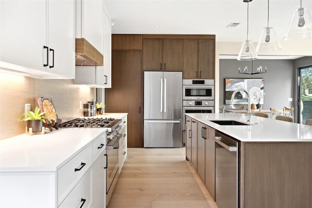 kitchen with range hood, stainless steel appliances, visible vents, white cabinets, and a sink