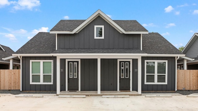 view of front of home featuring roof with shingles, board and batten siding, and fence