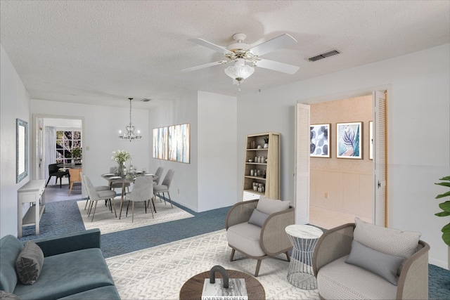 carpeted living area with visible vents, a textured ceiling, and ceiling fan with notable chandelier