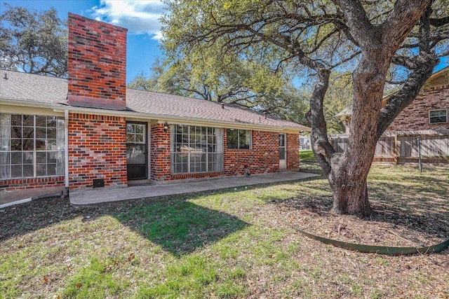 back of house with brick siding, a chimney, a patio area, and fence