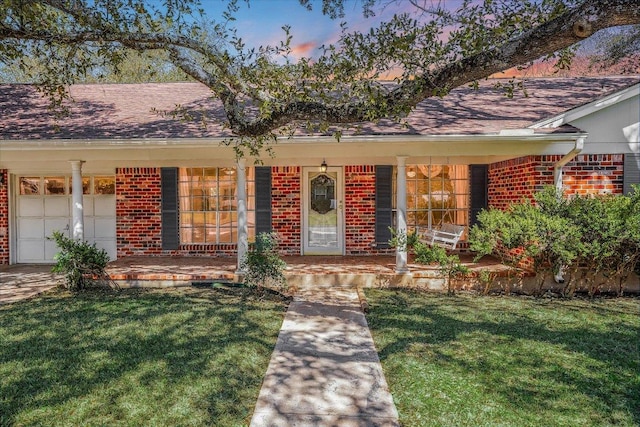 view of front of house featuring brick siding, a front lawn, and a porch