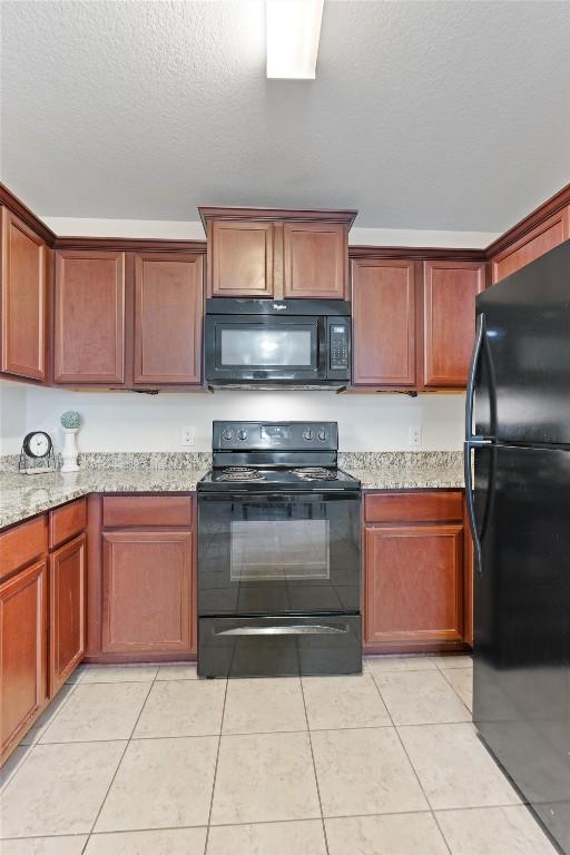 kitchen featuring light stone countertops, black appliances, light tile patterned floors, and a textured ceiling