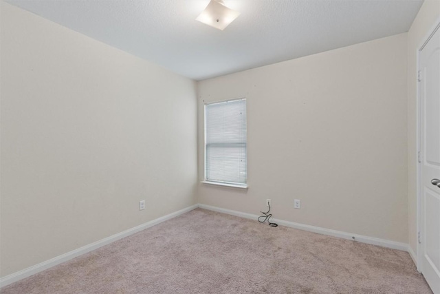 unfurnished room with baseboards and light colored carpet