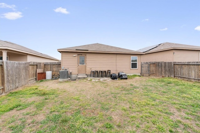 rear view of house with cooling unit, a fenced backyard, and a yard