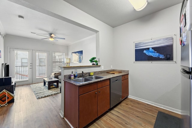 kitchen featuring stainless steel appliances, light wood-style floors, french doors, and a sink