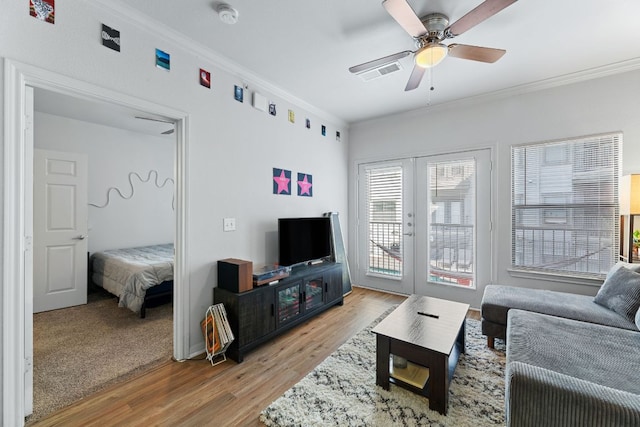 living room with a ceiling fan, light wood-style floors, visible vents, french doors, and crown molding