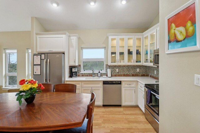 kitchen featuring white cabinetry, stainless steel appliances, backsplash, and a sink