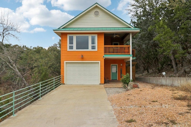 view of front of property with concrete driveway, fence, a balcony, metal roof, and a garage