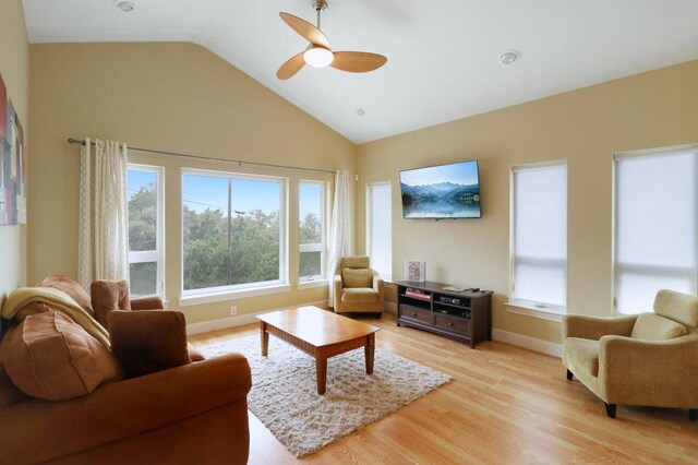 living area with light wood finished floors, a ceiling fan, a wealth of natural light, and baseboards