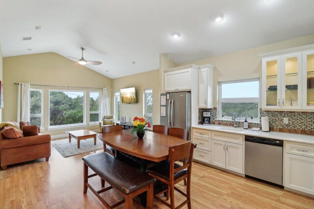 dining area featuring light wood-type flooring, ceiling fan, and vaulted ceiling