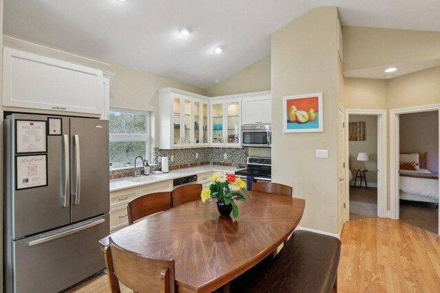 kitchen featuring light wood-style flooring, vaulted ceiling, a sink, and appliances with stainless steel finishes