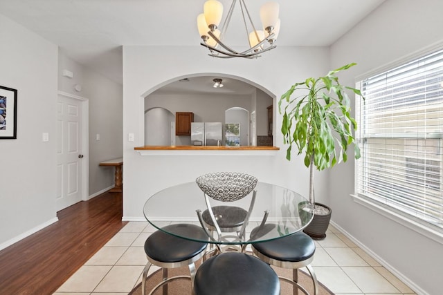 tiled dining space featuring baseboards and a chandelier