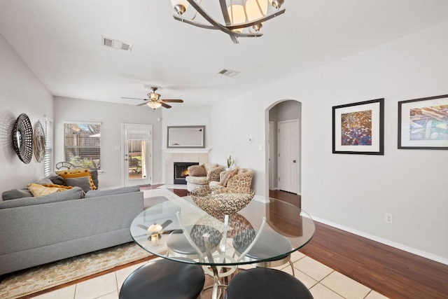 living room featuring baseboards, a fireplace, visible vents, and arched walkways