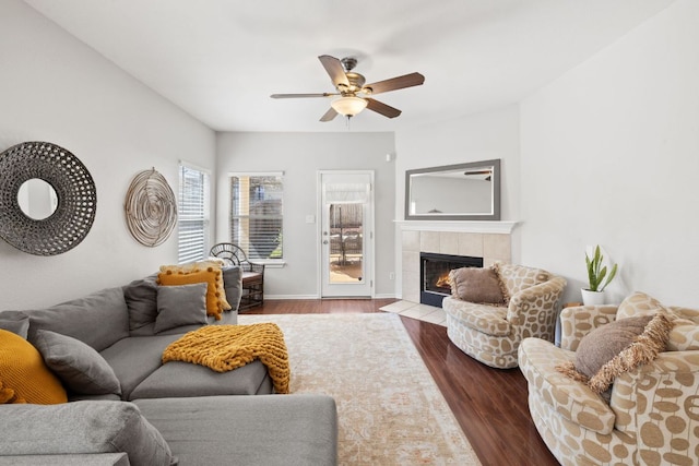 living area with baseboards, a fireplace, a ceiling fan, and wood finished floors