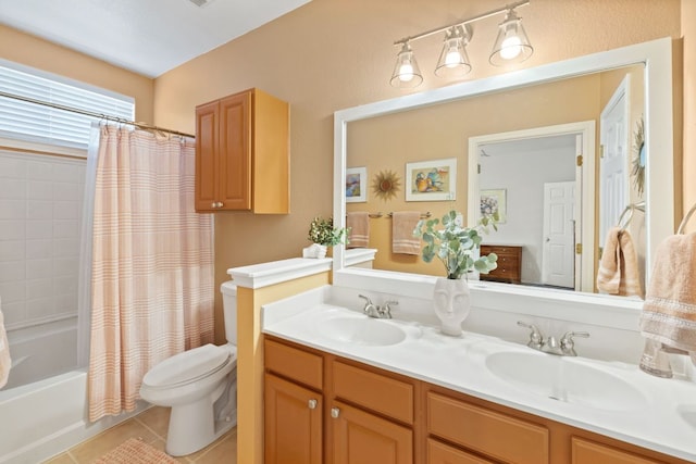 full bath featuring toilet, double vanity, a sink, and tile patterned floors