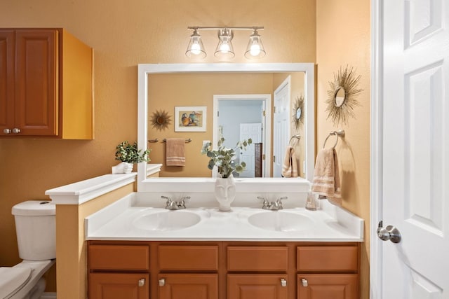 bathroom featuring toilet, double vanity, and a sink