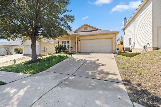 view of front of property featuring a garage, concrete driveway, central AC, and a front lawn