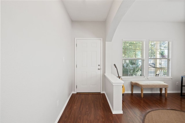 interior space featuring baseboards, arched walkways, and wood finished floors