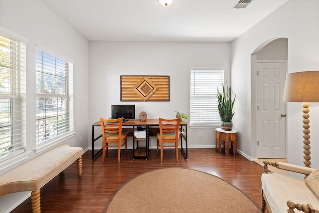 office space with arched walkways, wood finished floors, a wealth of natural light, and baseboards