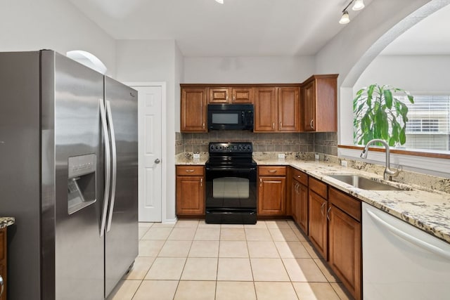 kitchen with a sink, backsplash, black appliances, and light tile patterned floors